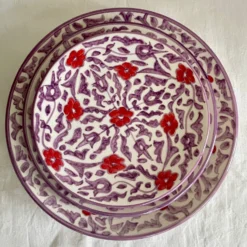 Ensemble d'assiette en céramique artisanale avec motifs floraux rouges et violets, fabriquée à la main.