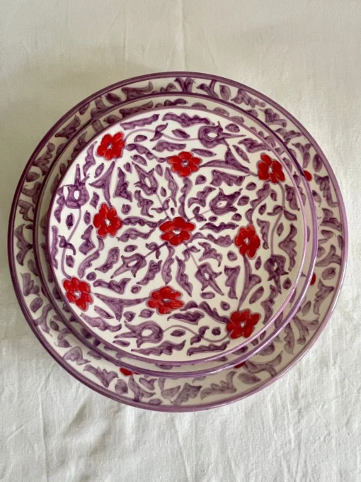 Ensemble d'assiette en céramique artisanale avec motifs floraux rouges et violets, fabriquée à la main.